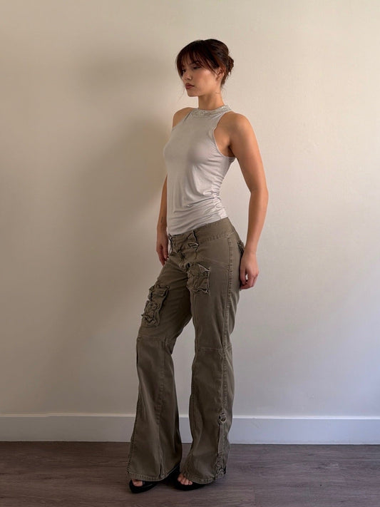 Person wearing a sleeveless top and cargo pants against a plain wall.