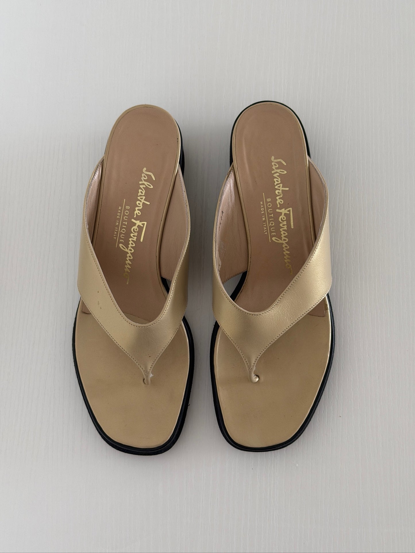 Pair of beige sandals with black soles on a light gray background