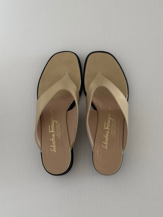 Pair of beige sandals with black soles on a light gray background