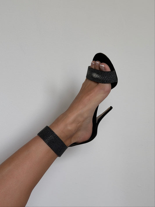 Black high-heeled sandal with glittery straps on a neutral background