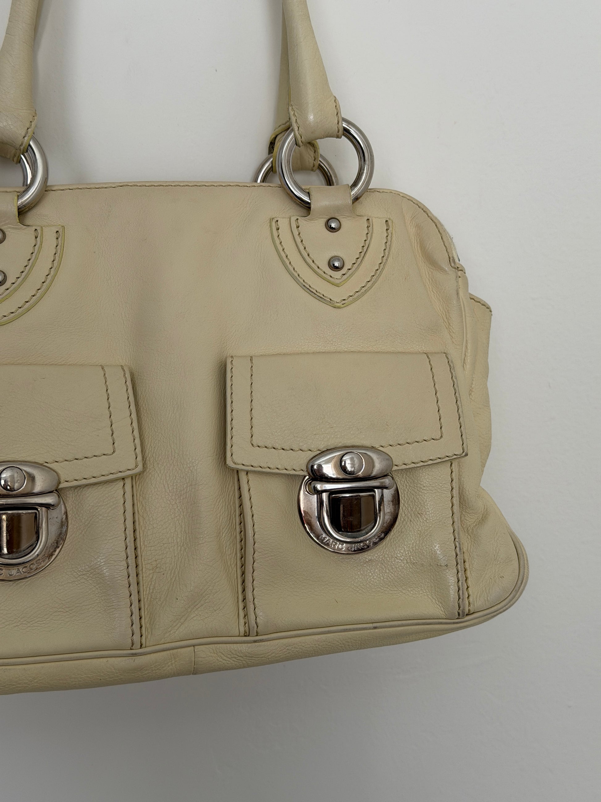 Beige handbag with metal hardware on a light gray background