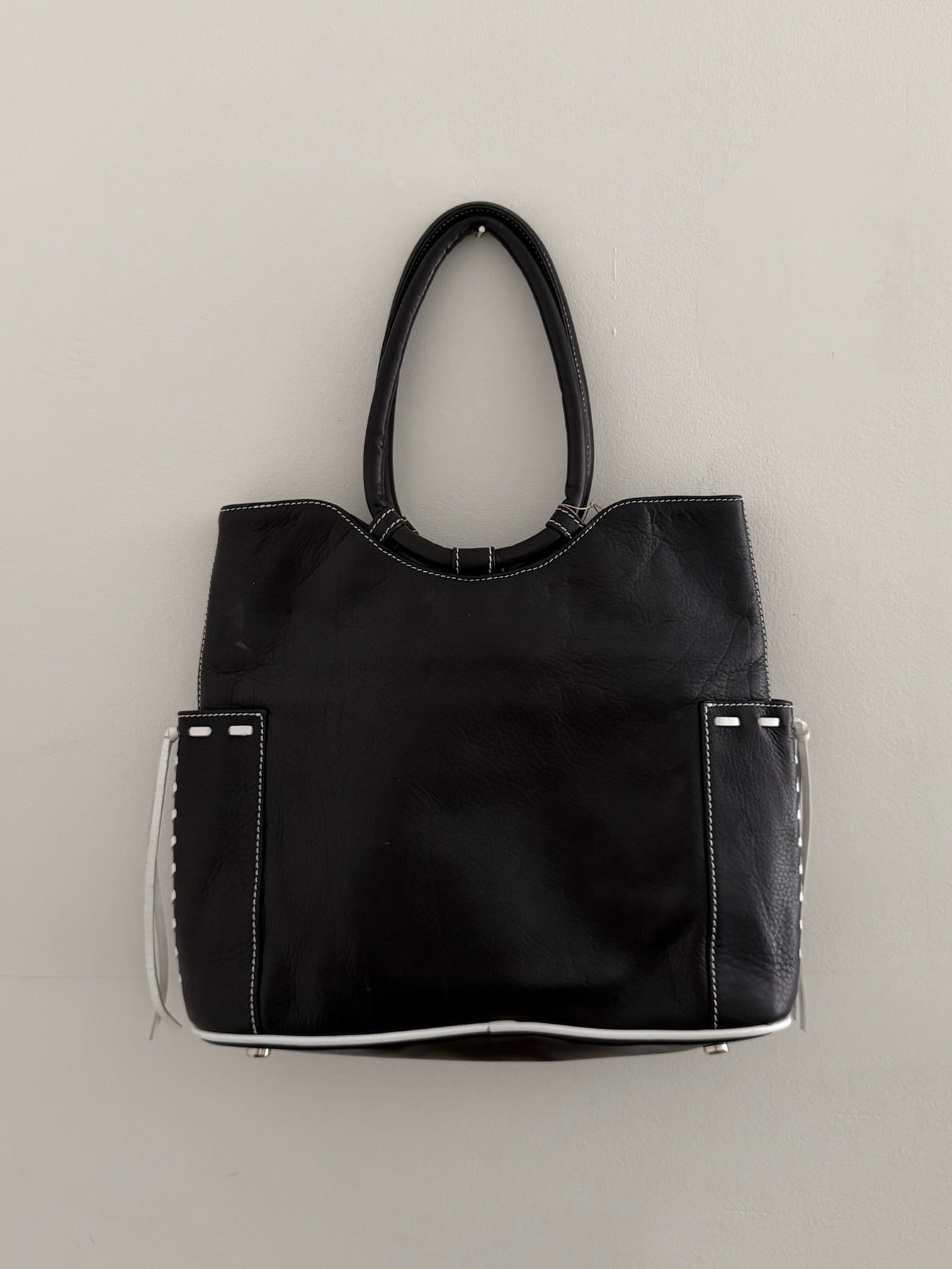 Black handbag with white accents on a light gray background