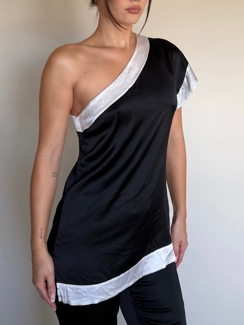 Woman wearing a black and white satin top against a plain background