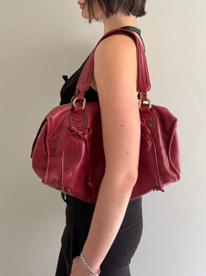 Woman carrying a red handbag against a plain background