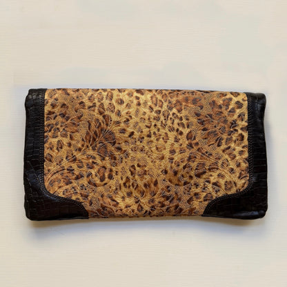 A rectangular clutch wallet featuring a central leopard print panel in beige and brown, framed by black crocodile-embossed leather borders on a light off-white background.