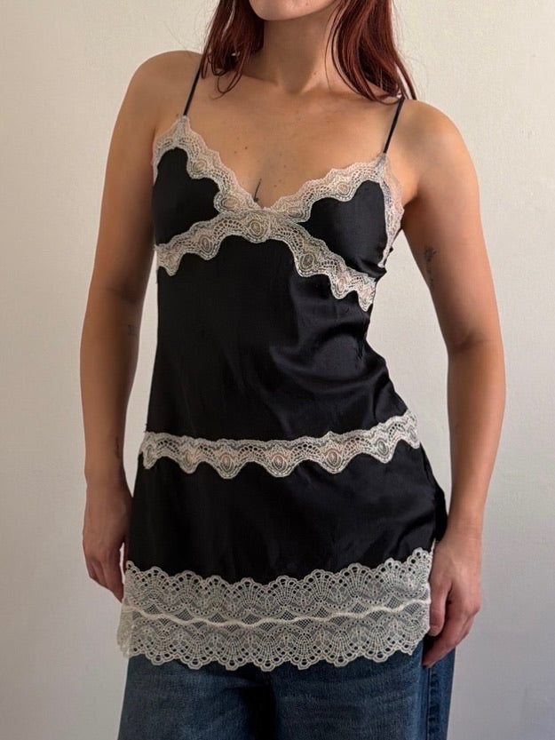 Black lace-trimmed top worn by a person on a plain background