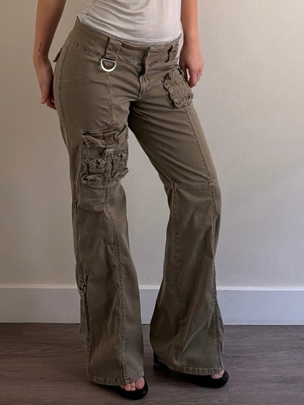 Woman wearing a sleeveless top and cargo pants against a plain wall.