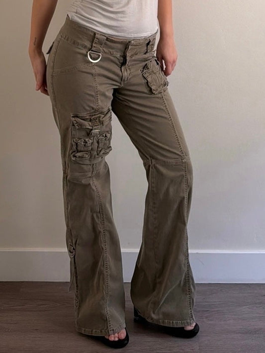 Woman wearing a sleeveless top and cargo pants against a plain wall.