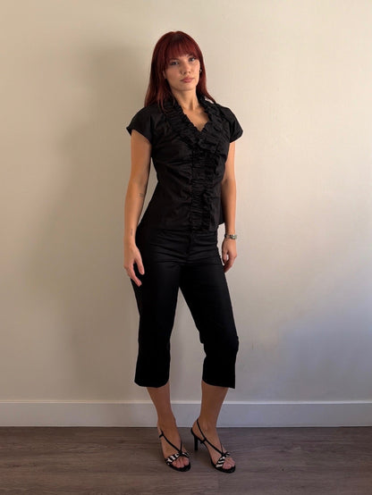 Woman wearing a black outfit against a plain wall