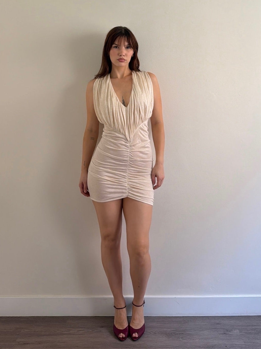 Woman wearing a beige dress against a plain wall