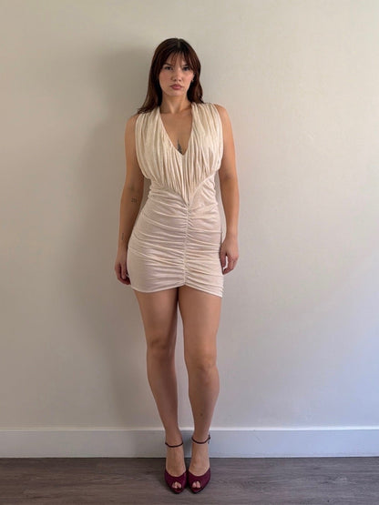 Woman wearing a beige dress against a plain wall