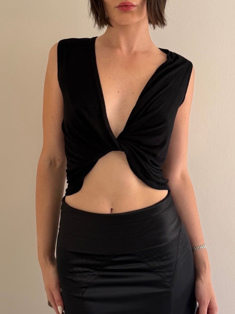 Woman wearing a black sleeveless top with a deep neckline and cutout design.