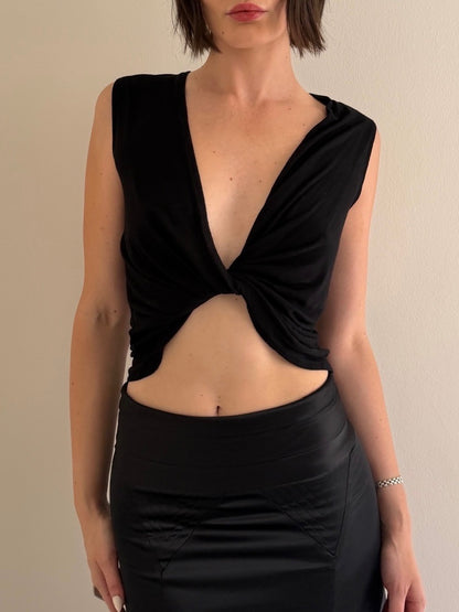 Woman wearing a black sleeveless top with a deep neckline and cutout design.