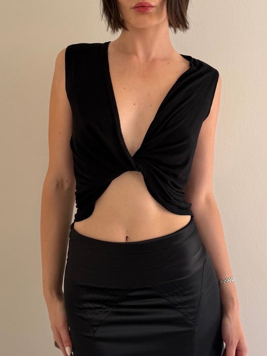 Woman wearing a black sleeveless top with a deep neckline and cutout design.