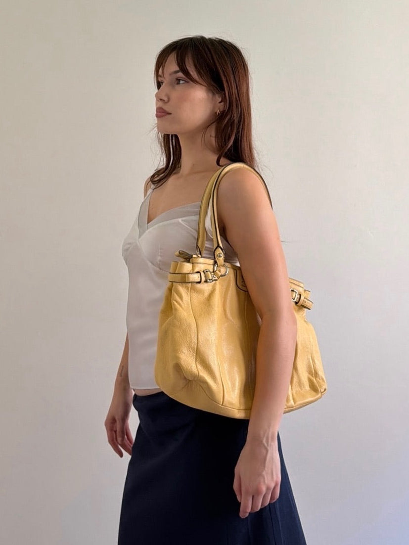 Woman holding a yellow handbag against a plain background