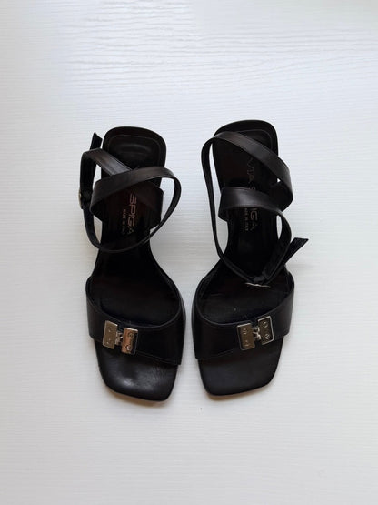 Black high-heeled sandals with gold buckles on a white background