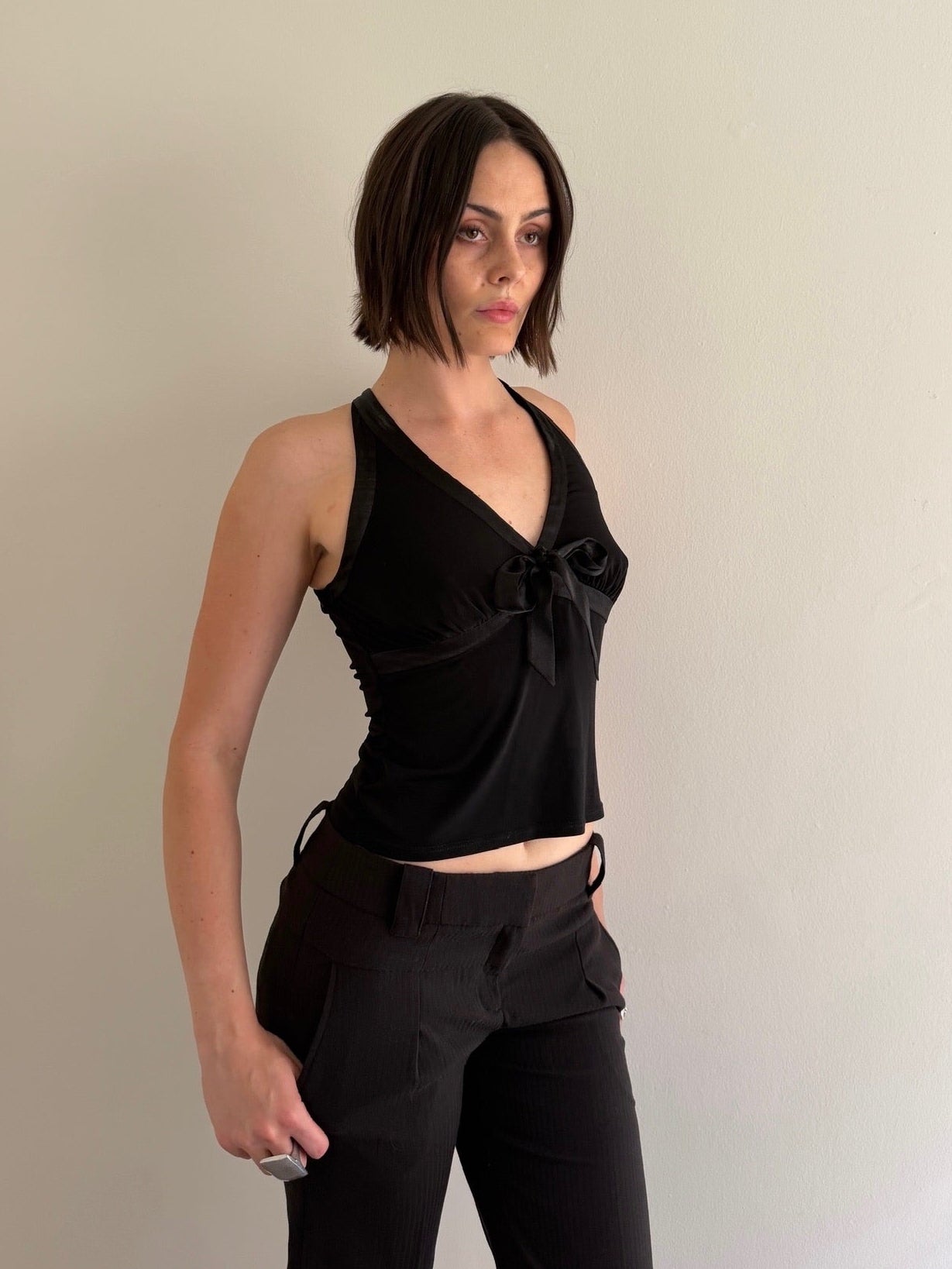 Woman wearing a black sleeveless top and pants against a plain background