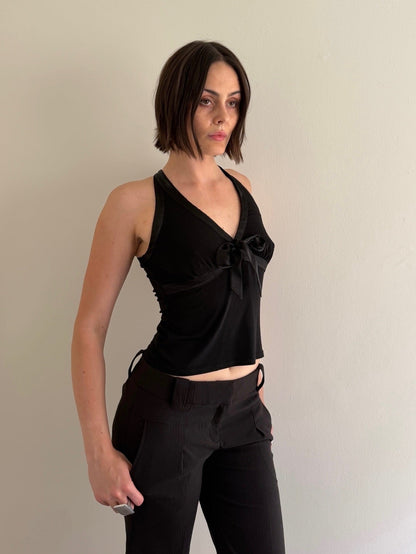 Woman wearing a black sleeveless top and pants against a plain background