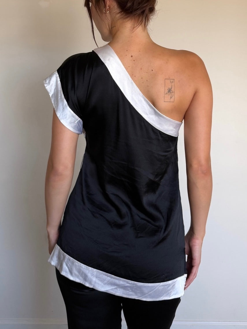 Person wearing a black and white one-shoulder top against a plain background