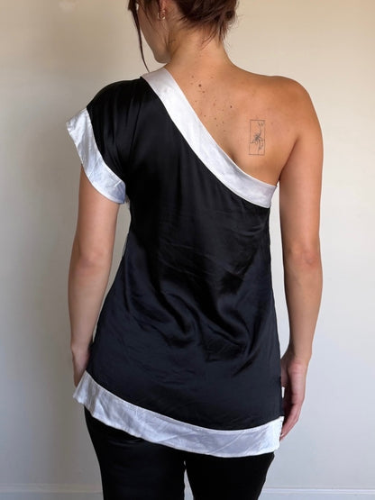 Person wearing a black and white one-shoulder top against a plain background