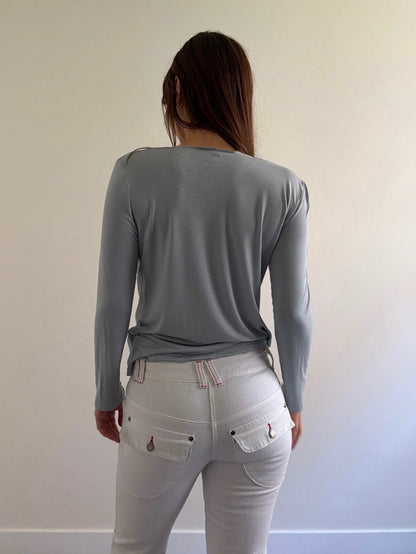 Person wearing a gray long-sleeve top and light gray pants against a plain background