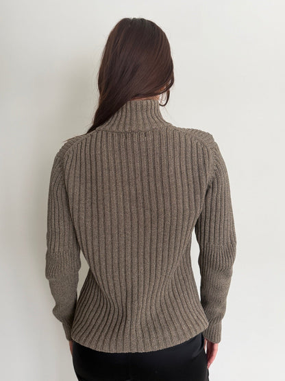 Person wearing a brown ribbed sweater against a white background