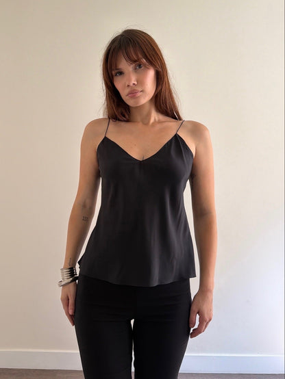Woman wearing a black spaghetti strap top against a plain background