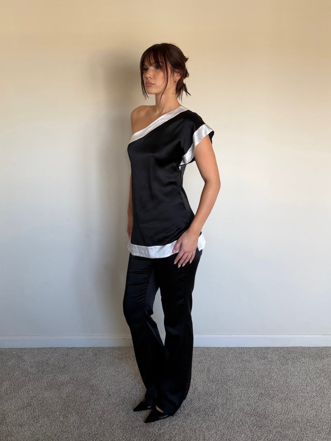 Woman wearing a black and white outfit against a plain wall.