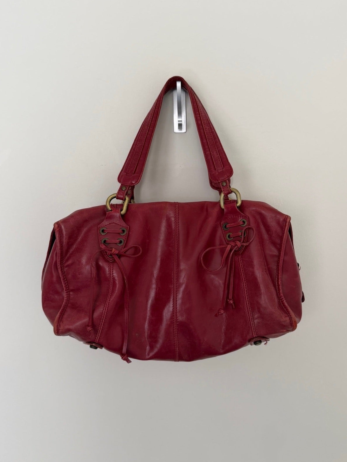 Red handbag hanging on a white wall