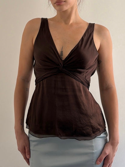 Woman wearing a brown sleeveless top with a plain background