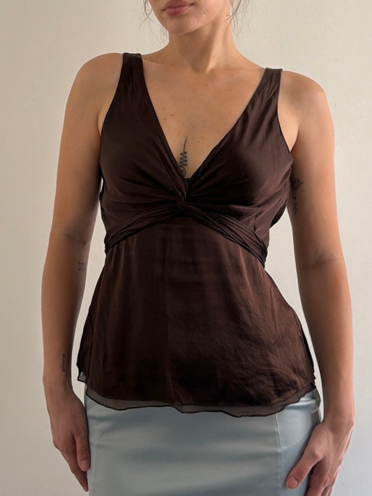 Woman wearing a brown sleeveless top with a plain background