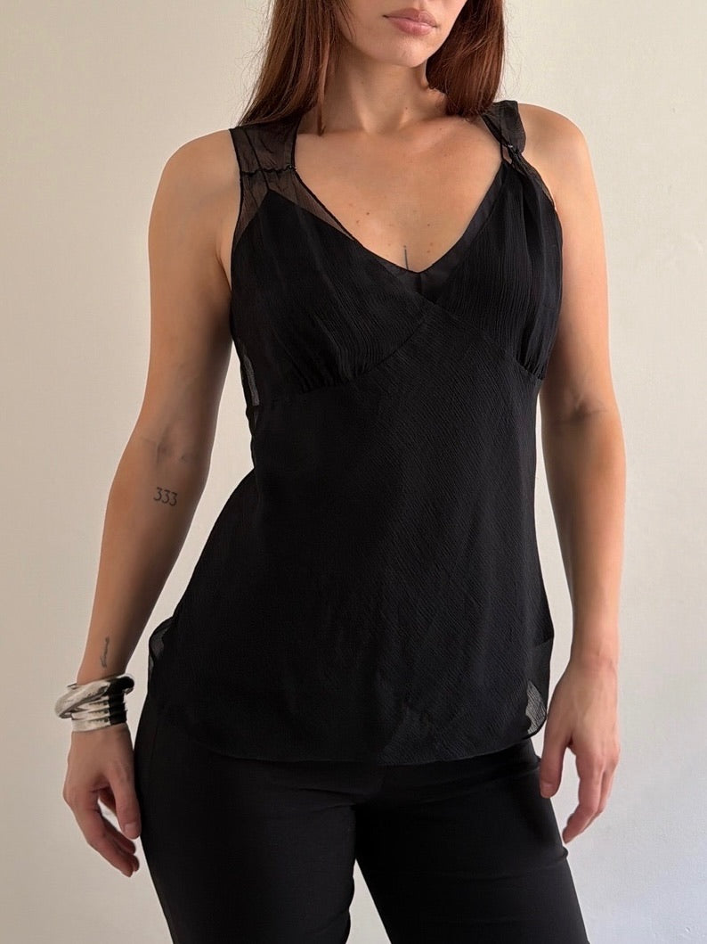 Woman wearing a black sleeveless top with a plain background
