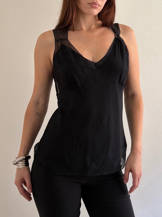 Woman wearing a black sleeveless top with a plain background