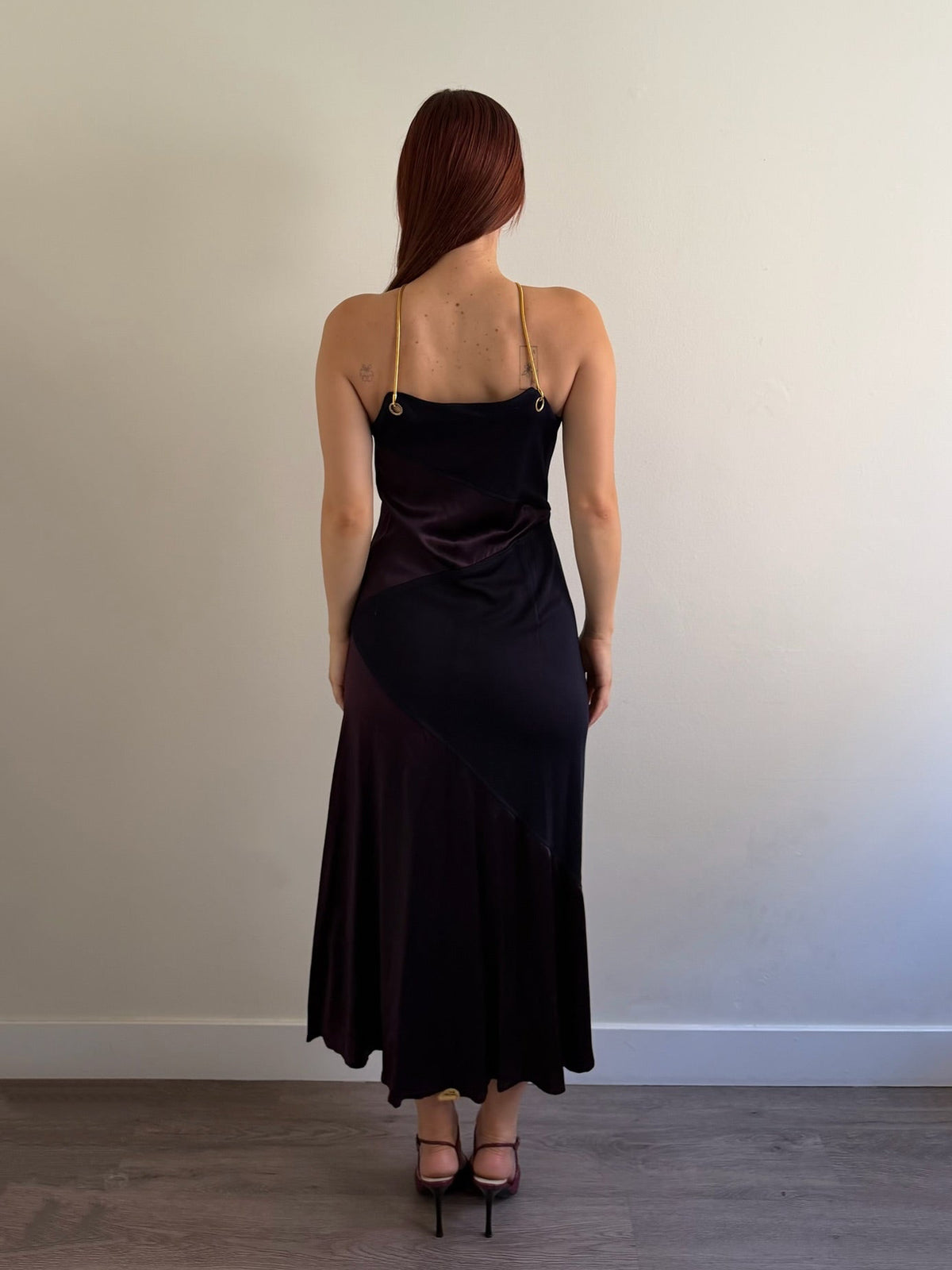back of halter neck dress with red shoes infant of white wall
