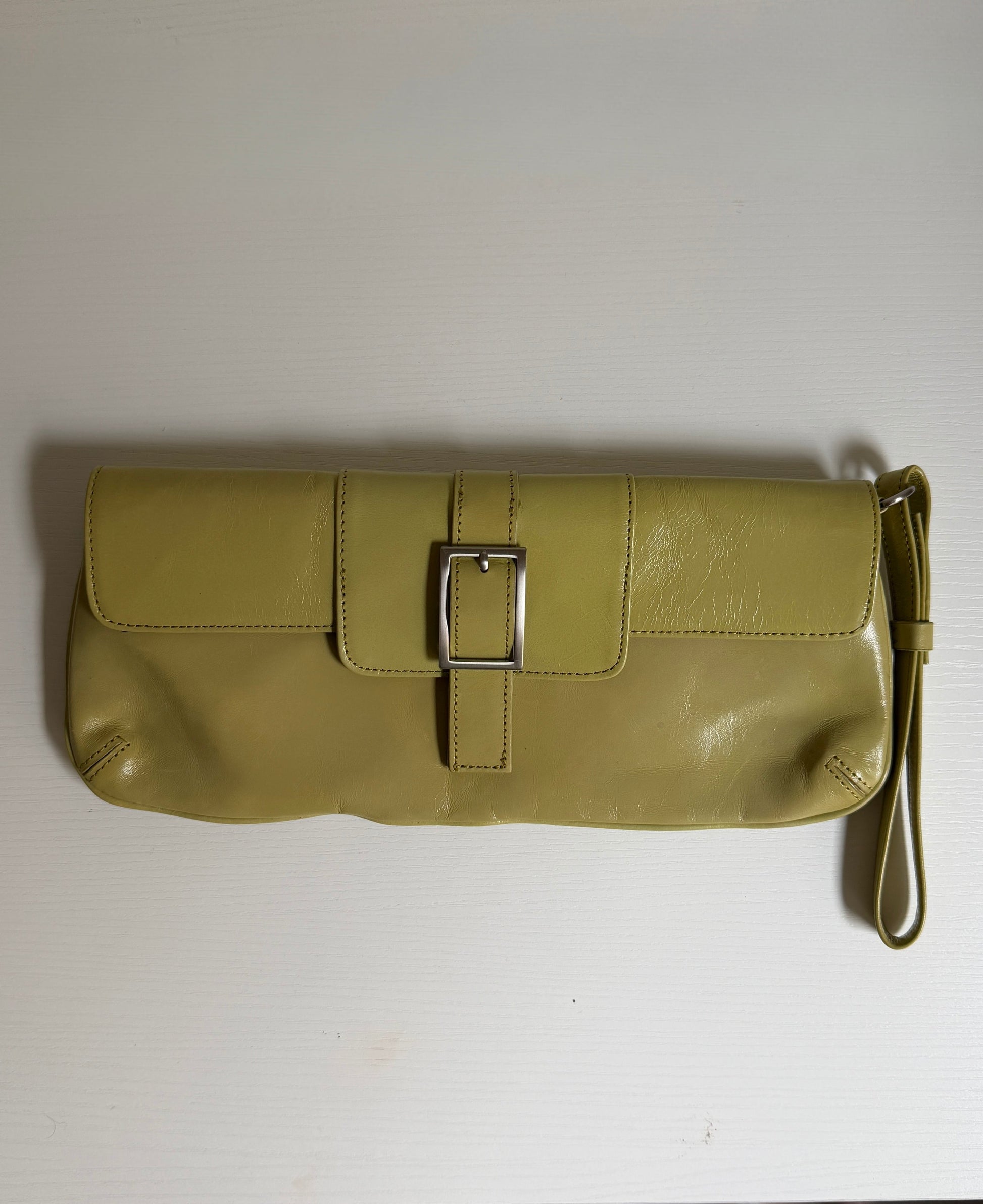Green clutch bag with a buckle on a white surface