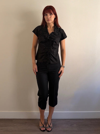 Woman wearing a black outfit against a plain wall