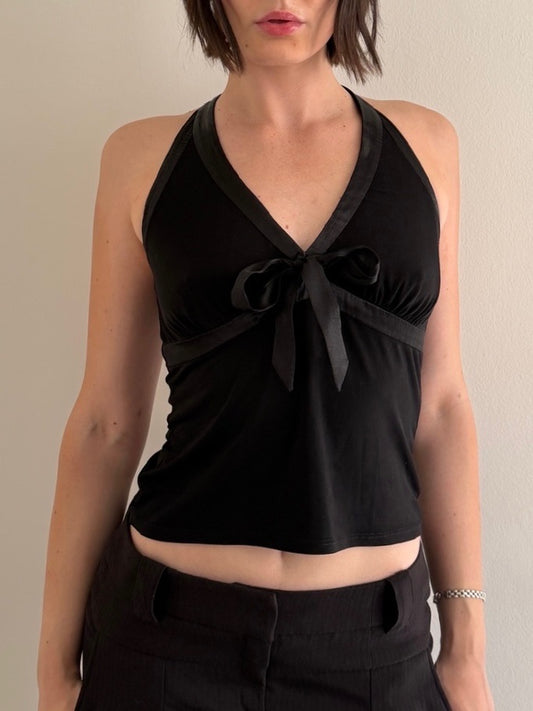 Black halter top with a tie detail worn by a person on a neutral background
