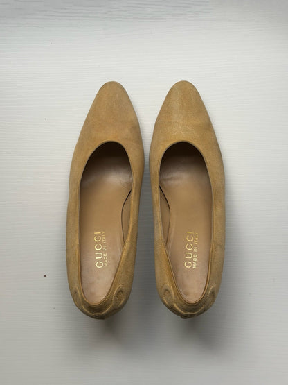 A pair of Gucci suede pointed-toe pumps in a tan color, shown from a top-down view on a light gray background.