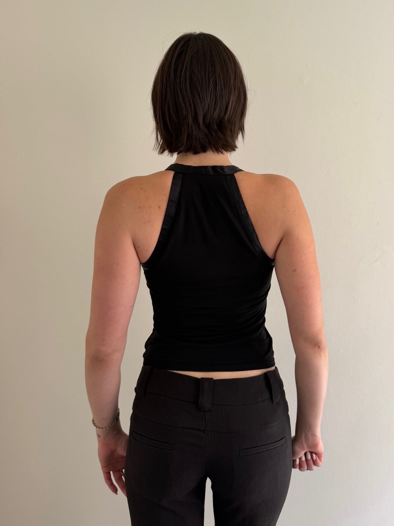 Person wearing a black sleeveless top and black pants against a plain background