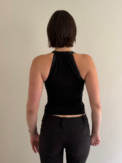 Person wearing a black sleeveless top and black pants against a plain background