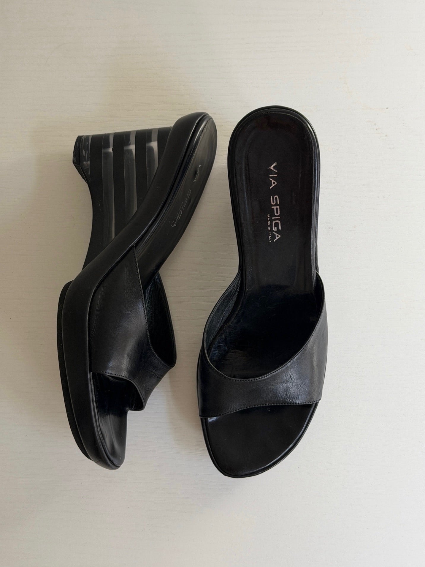 Black high-heeled shoes with 'Via Spiga' branding on a light background