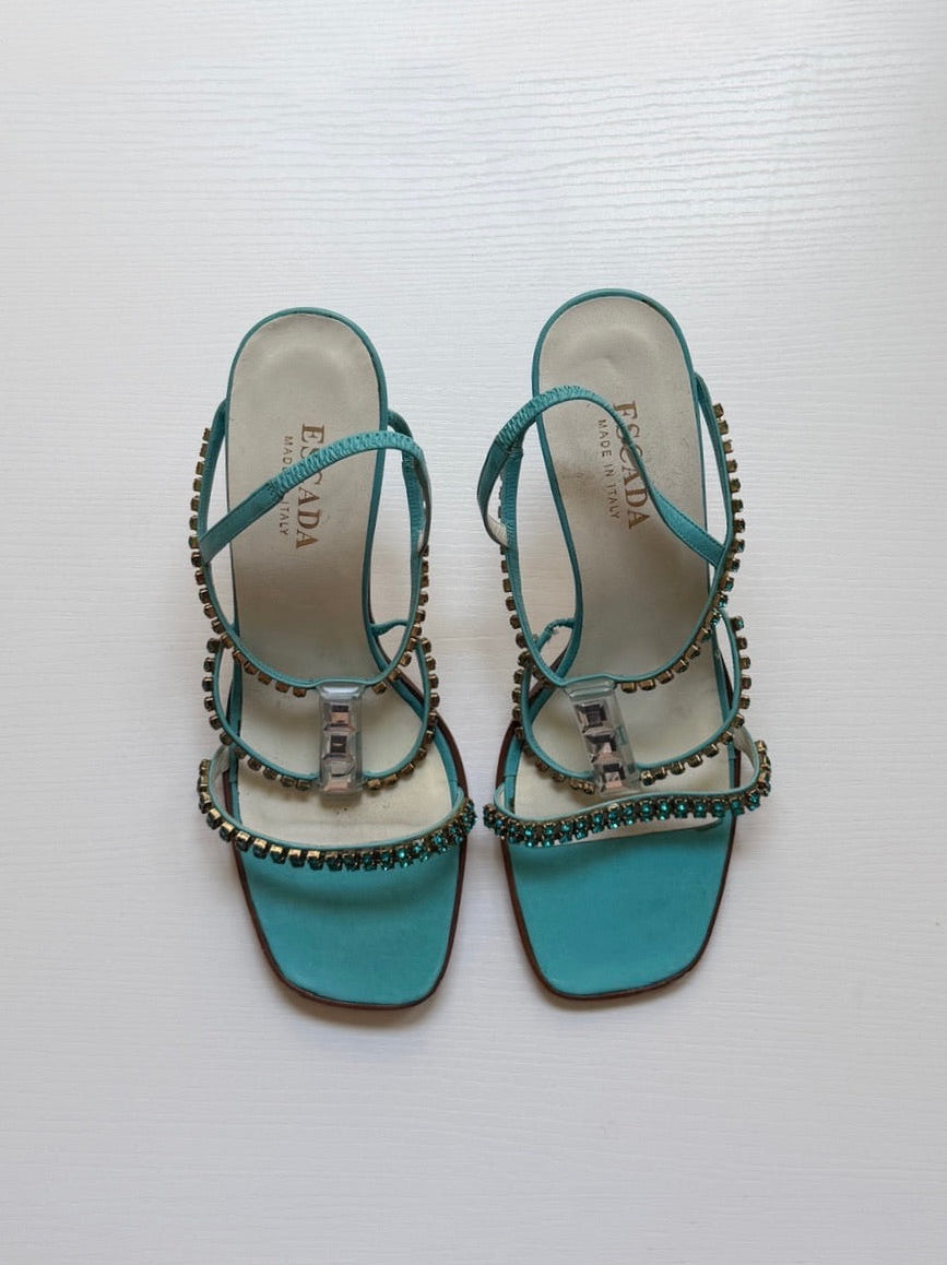 Turquoise sandals with decorative straps on a white background
