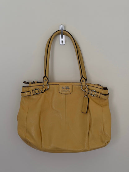 Yellow handbag with visible brand logo on a beige background
