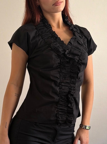 Woman wearing a black ruffled blouse against a plain background