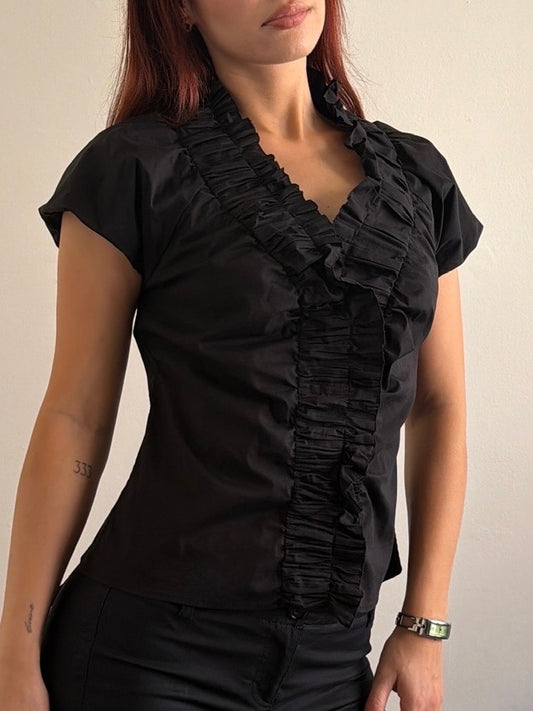 Woman wearing a black ruffled blouse against a plain background