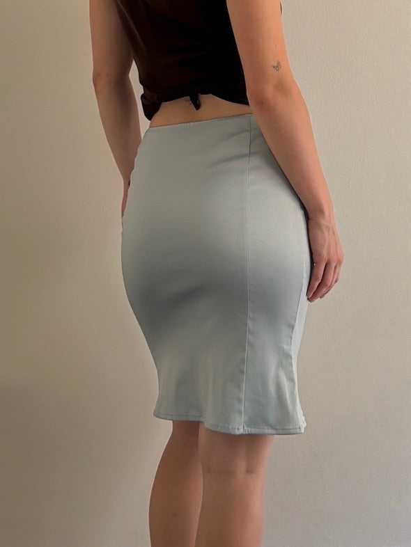 Person wearing a light gray skirt against a plain background