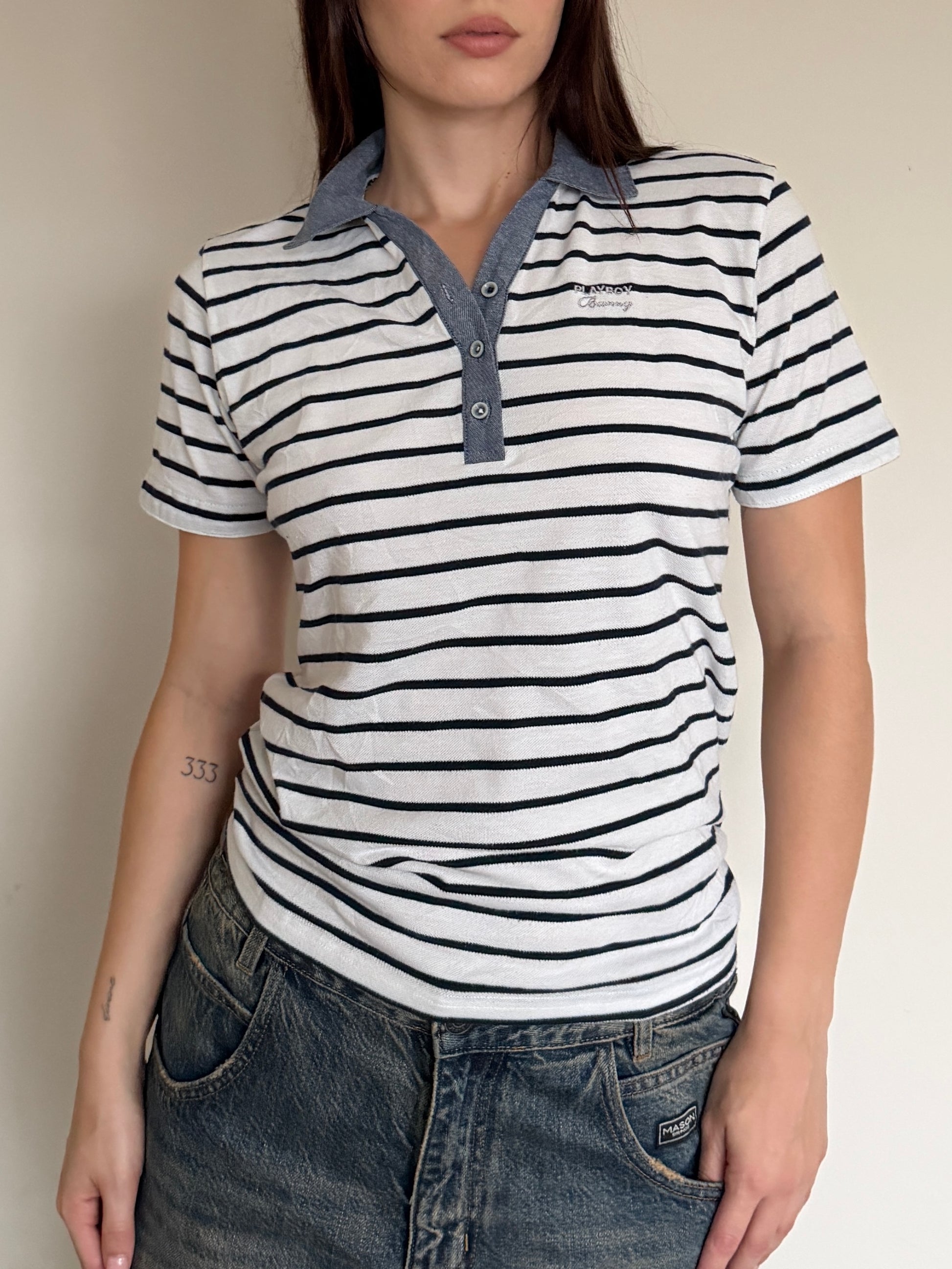 Person wearing a striped polo shirt with a visible brand logo against a neutral background