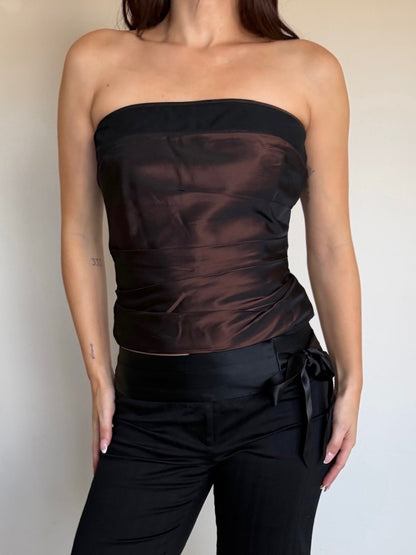 Person wearing a black strapless top and black pants against a plain background