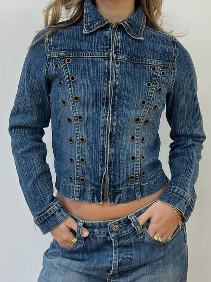 Person wearing a blue denim jacket on a plain background