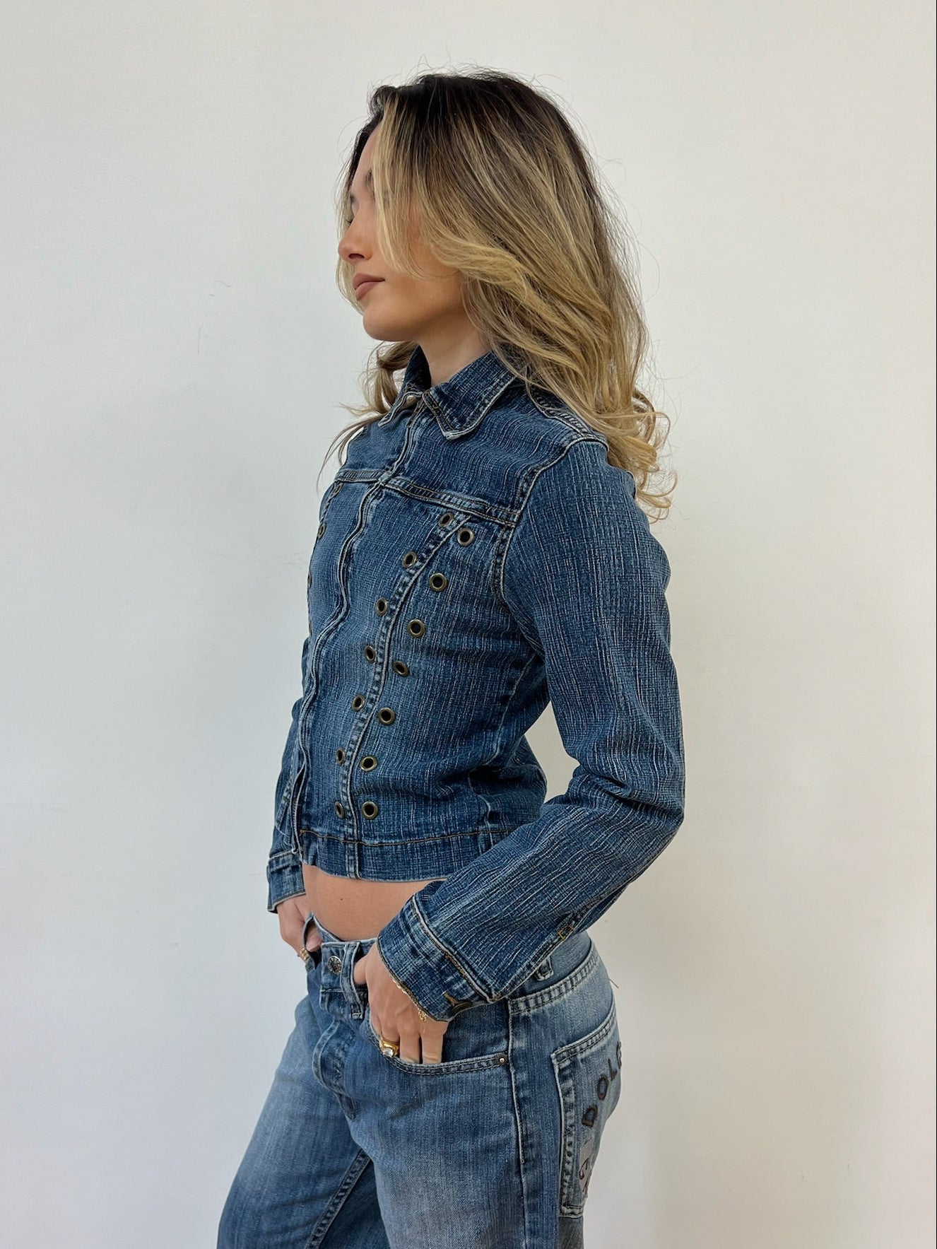 Woman wearing a blue denim jacket and jeans against a white background